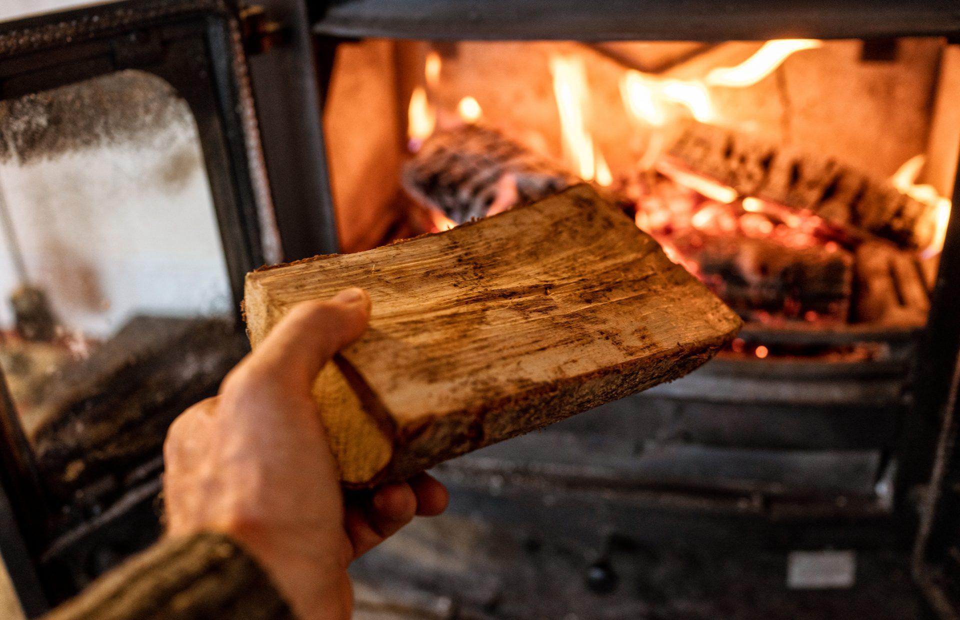 Putting a log into a wood burning stove Close-up of a log being put into a hot wood-burning stove.